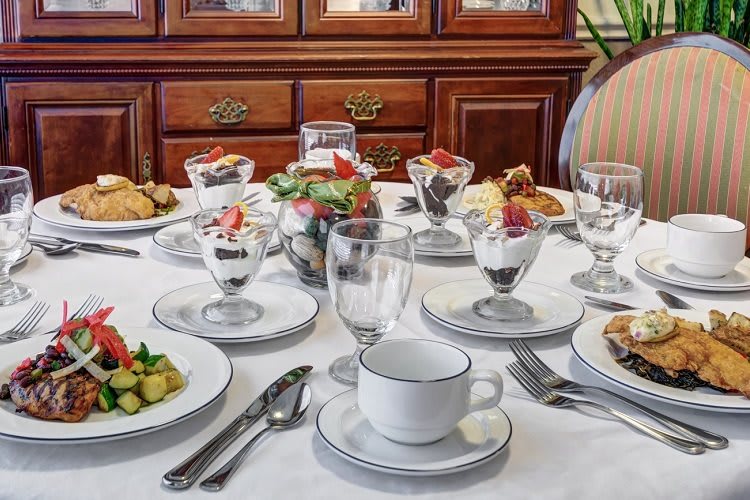 A beautifully set dining table with desserts and place settings ready for a formal meal.