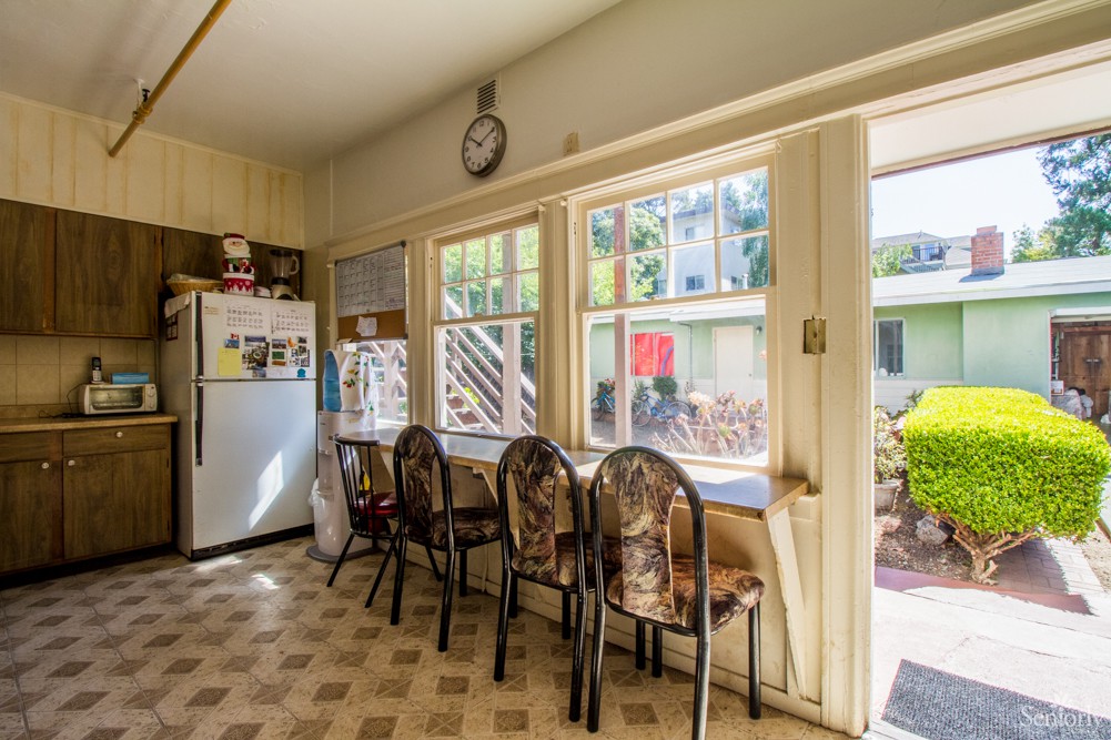 A vintage-style kitchen with a row of chairs by sunlit windows.