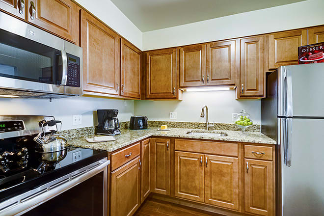 A modern kitchen with wooden cabinets and granite countertops equipped with various appliances.