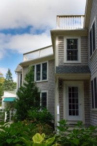 A residential house with a modern exterior featuring large windows and a small balcony.