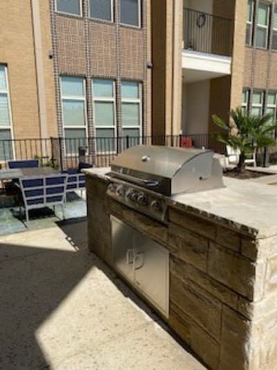 Outdoor patio area with a grill and seating in an apartment complex.