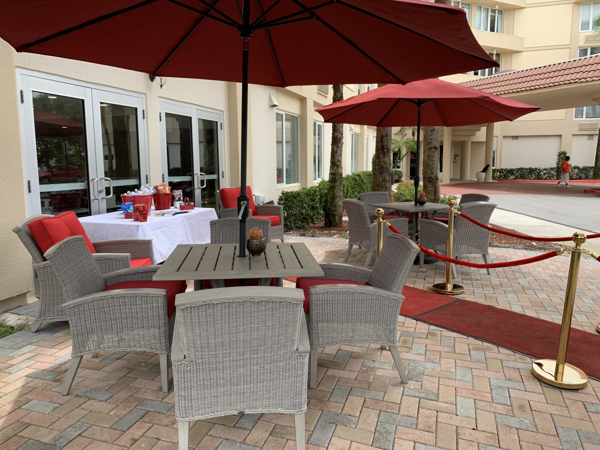 Outdoor patio area with wicker furniture and red umbrellas.