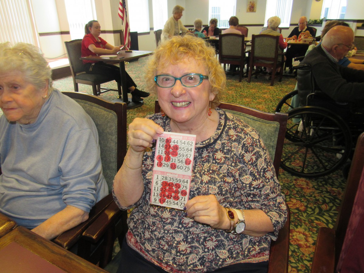 A woman holding a bingo card in a community setting.