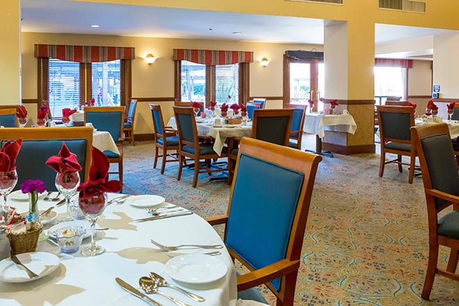 A spacious and elegantly set restaurant dining room with neatly arranged tables and chairs.