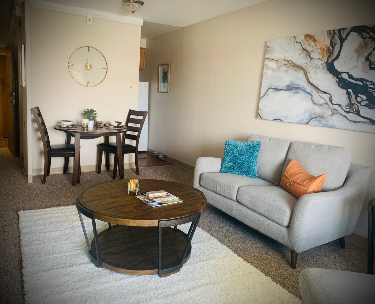 A cozy living room with a sofa, coffee table, and adjacent dining area.