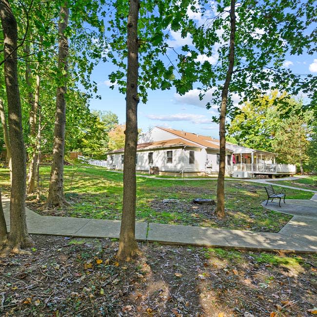 A house surrounded by trees with a pathway leading through the yard.