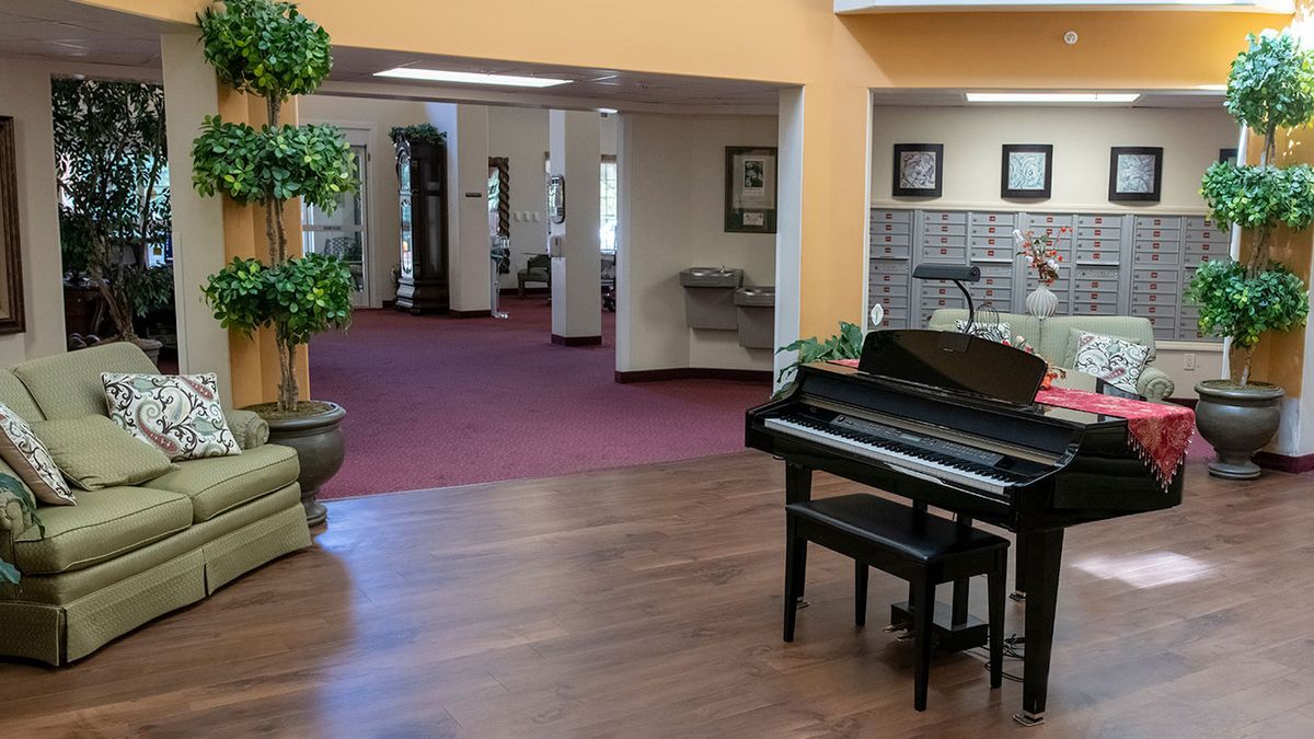 A spacious lobby area with a piano and decorative plants.
