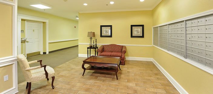 A cozy lobby area with a sofa, table, and decorative elements against a yellow wall.