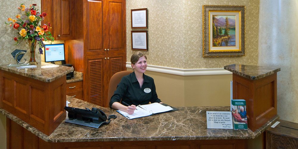 A receptionist working at a desk in a hospitality setting.