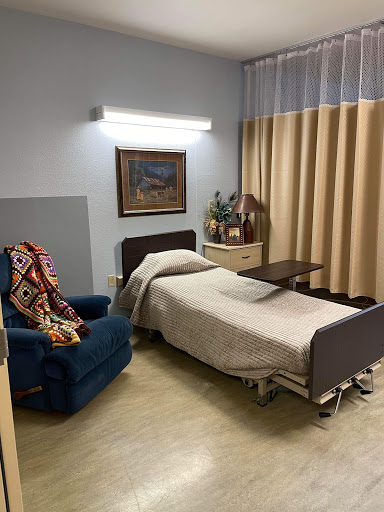 A cozy hospital room featuring a bed, a comfortable chair, and soft lighting.