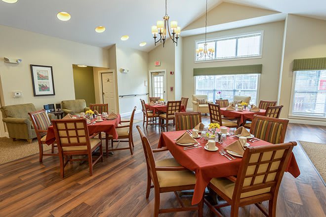 A well-lit dining area with multiple tables and chairs, elegantly set for a meal.