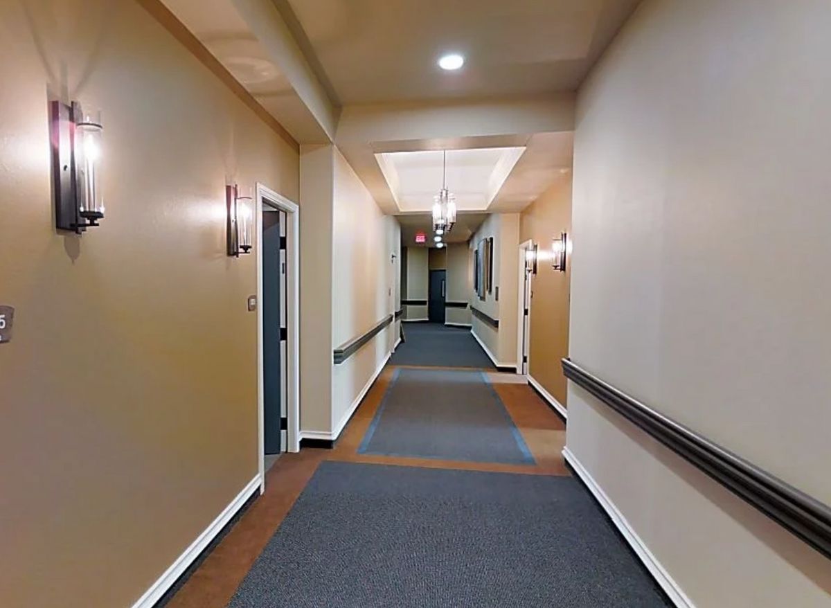 A well-lit hallway with doors and carpeted flooring.