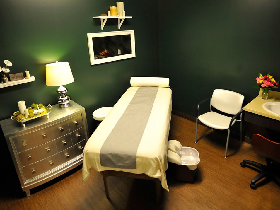A cozy massage room with a bed, ambient lighting, and comfortable seating.