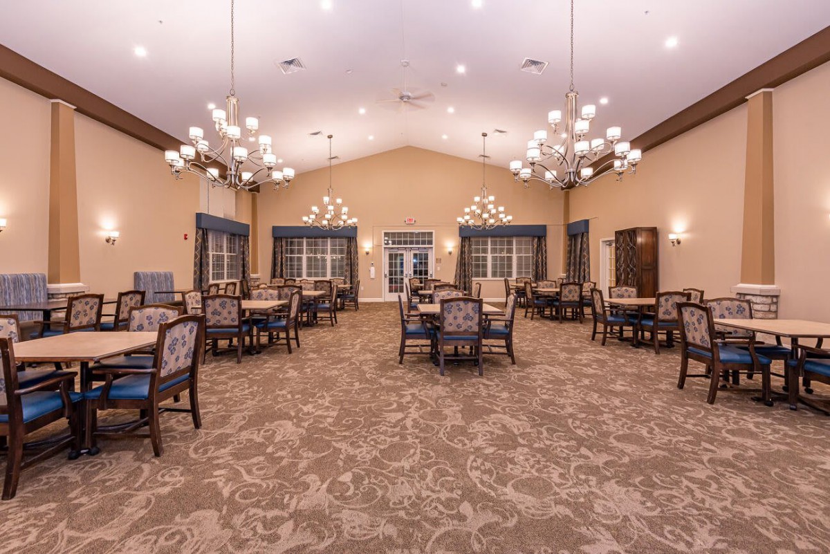 Spacious dining room with elegant chandeliers and neatly arranged tables and chairs.