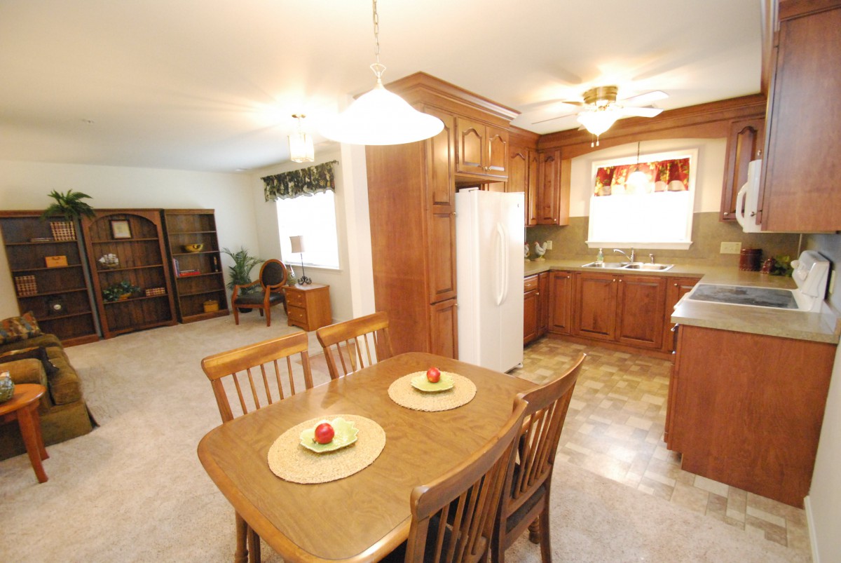 A cozy kitchen and dining area with wooden cabinetry and a table set for four.