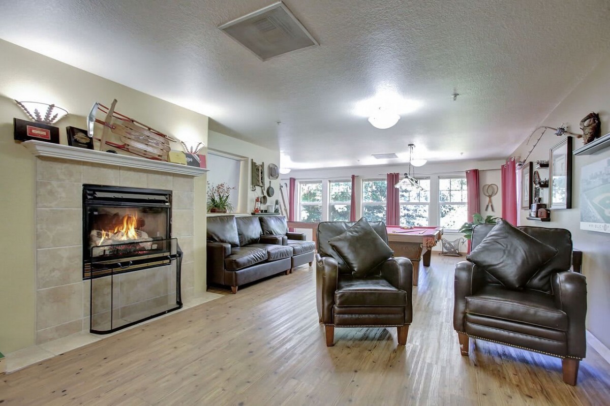 A cozy living room with a fireplace, leather chairs, and a pool table.