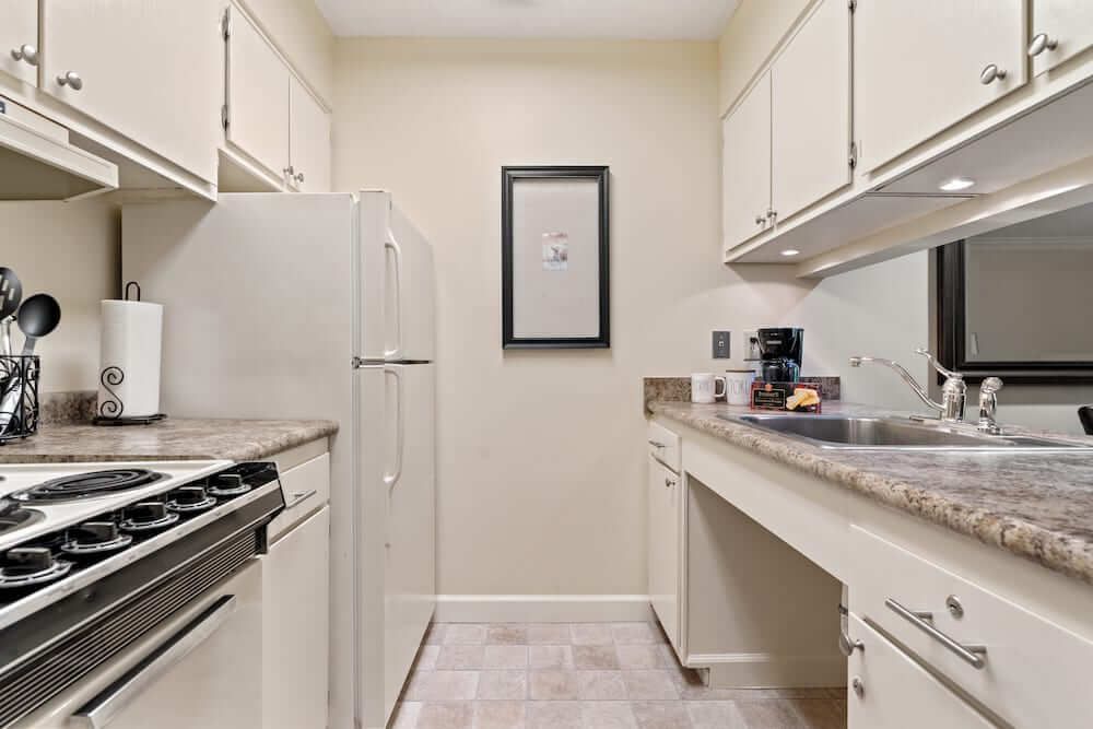 A compact kitchen with white cabinets and essential appliances.