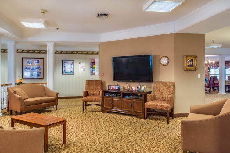 A cozy living room with a television, chairs, and a coffee table on a carpeted floor.