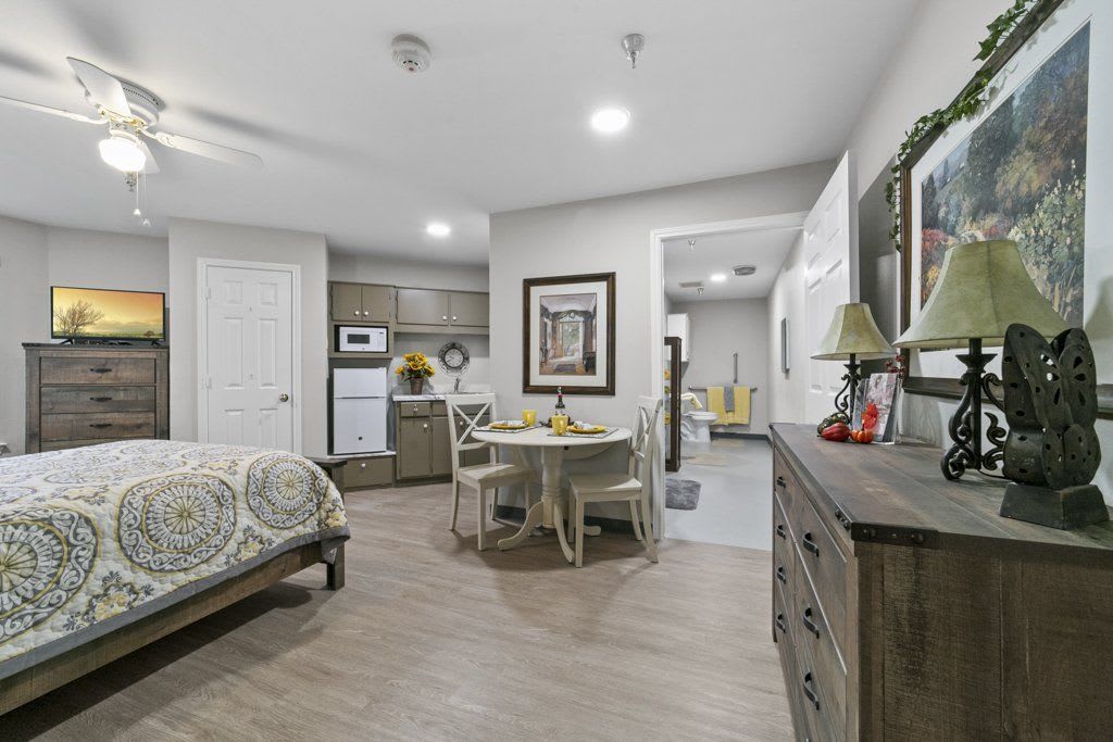 A cozy studio apartment interior with a bedroom, kitchenette, and dining area.