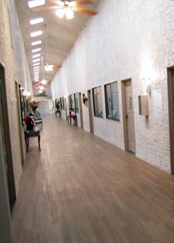 A long hallway with wooden flooring and doors along the sides.