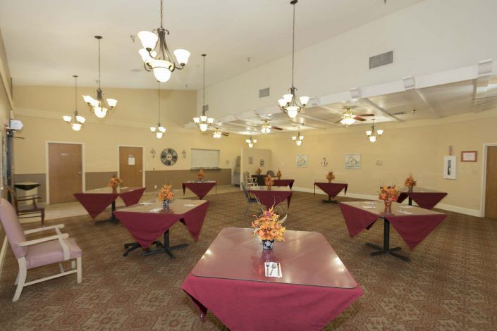 A spacious dining room with elegantly set tables and decorative chandeliers.