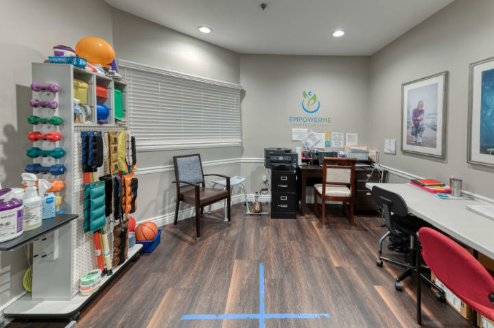 A well-organized office space with a desk, chairs, and storage shelves containing various equipment.