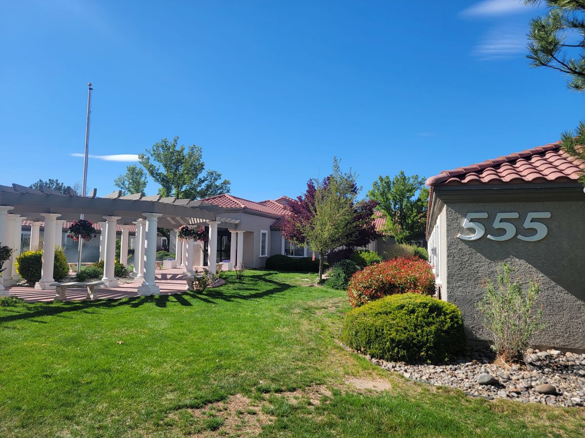 A scenic view of a house with a well-maintained garden and clear blue sky.