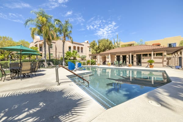 A serene outdoor swimming pool surrounded by palm trees, perfect for relaxation under a sunny sky.