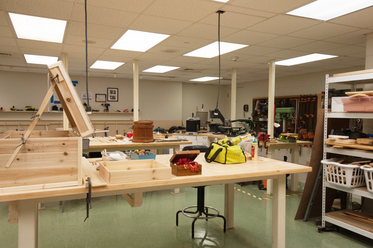 A well-equipped woodworking workshop with tools and equipment on large tables.