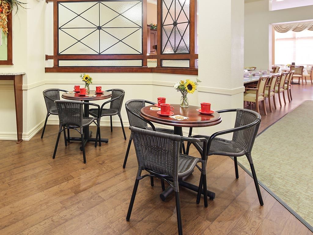 A cozy cafe dining area with neatly arranged tables, decorated with sunflowers and red place settings.