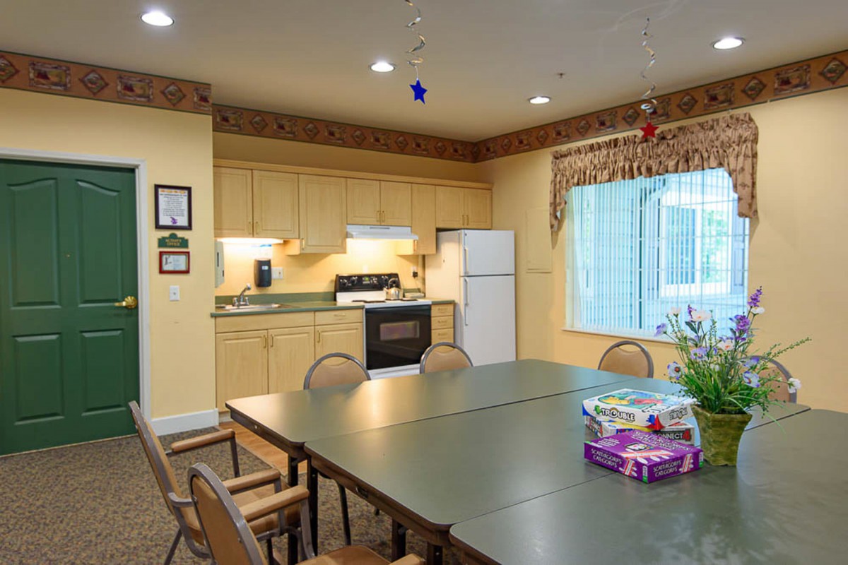 A cozy kitchen and dining area featuring a large table surrounded by chairs, with a stove, refrigerator, and cabinets in the background.