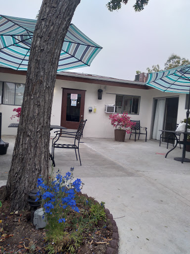 A serene outdoor patio area featuring colorful flowers, seating arrangements, and umbrellas for shade.