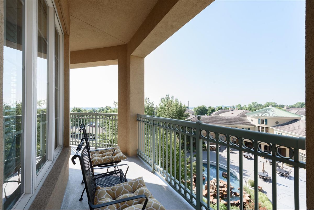A sunny balcony with comfortable chairs overlooking a scenic view.