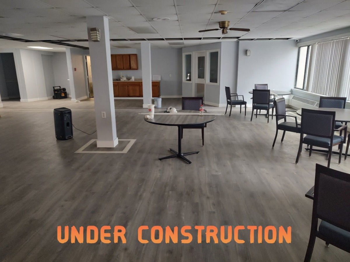 An interior space under construction with tables and chairs placed around.