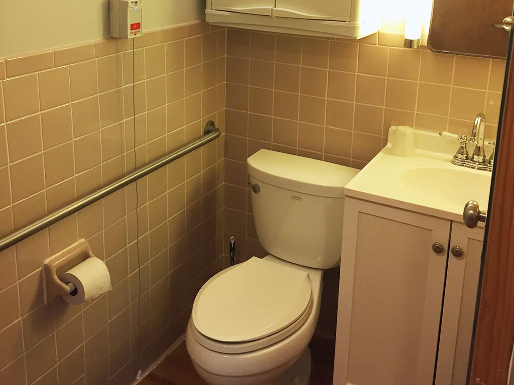 A small bathroom with a toilet, sink, and tiled walls.