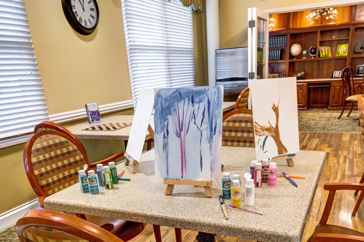 Art station with paintings and supplies set up indoors on a table.