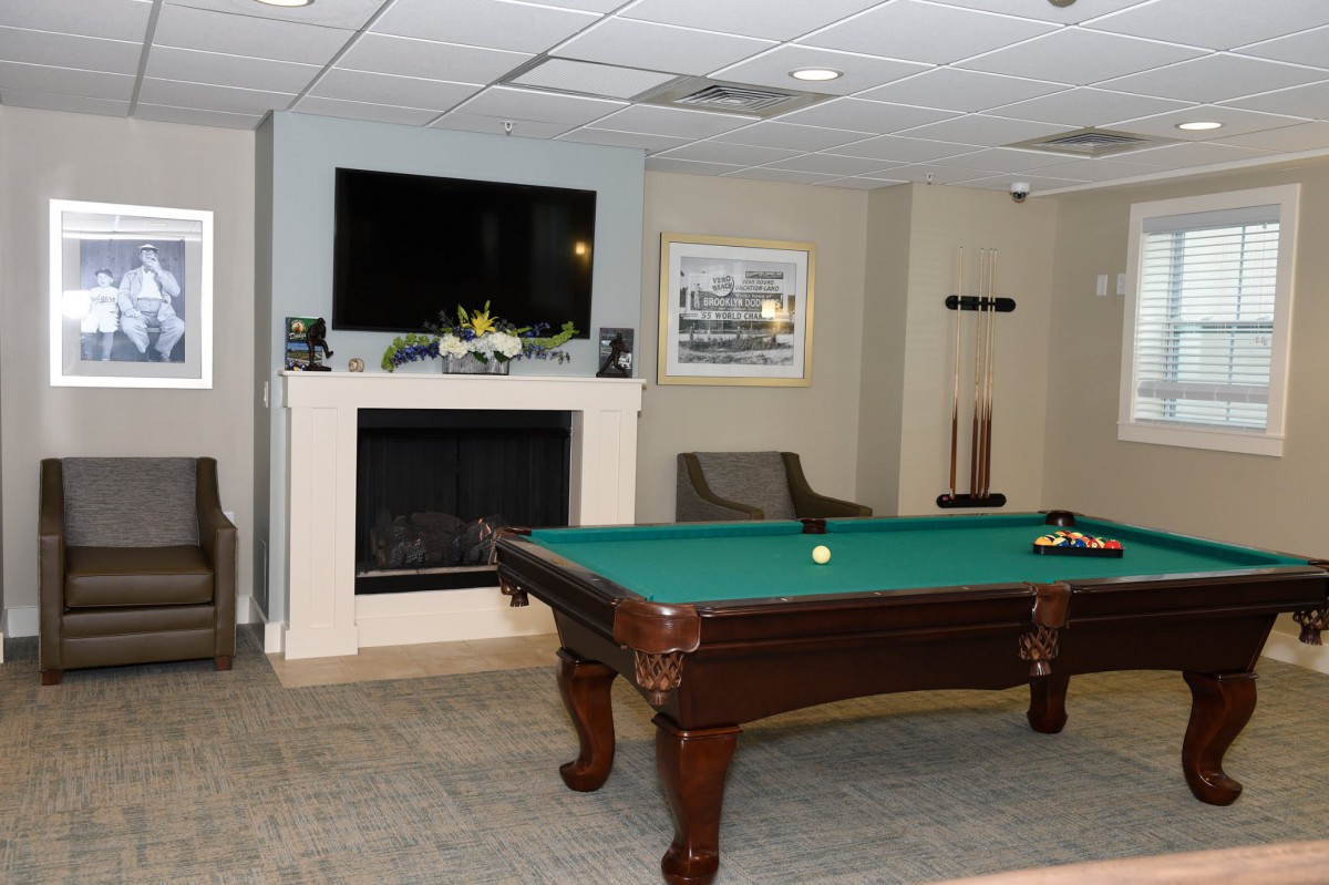A cozy billiard room featuring a pool table, fireplace, and television.
