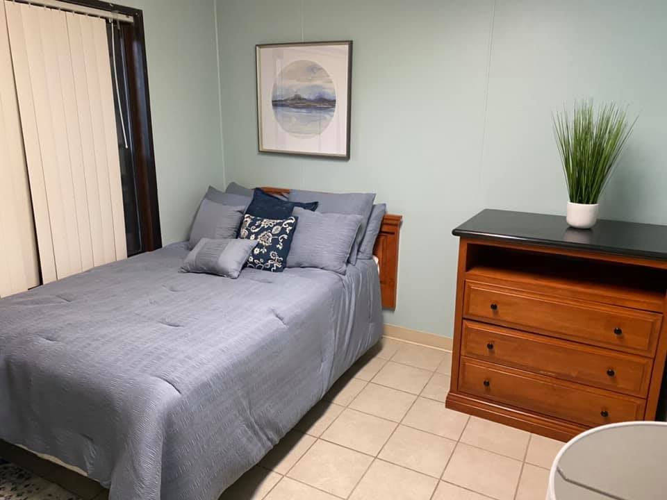 A cozy bedroom with a neatly made bed, wooden dresser, and minimalist decor.