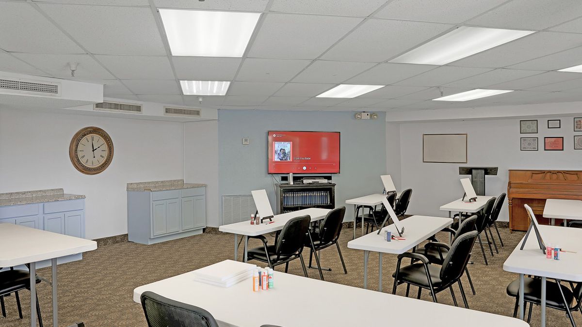 A modern classroom or training room with tables and chairs arranged facing a projector screen.