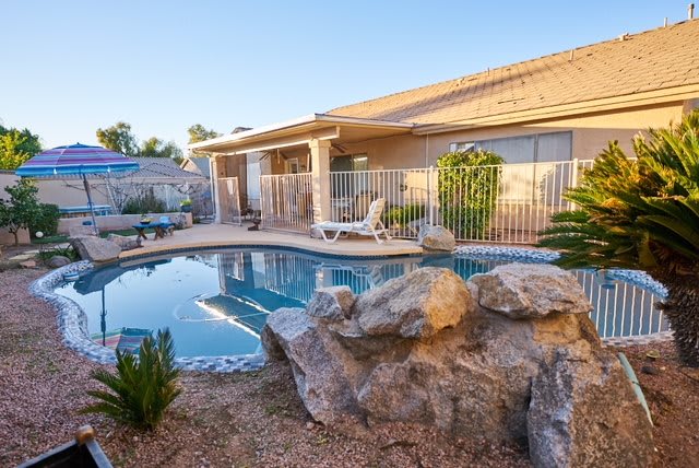A residential backyard featuring a swimming pool surrounded by rocks and plants.
