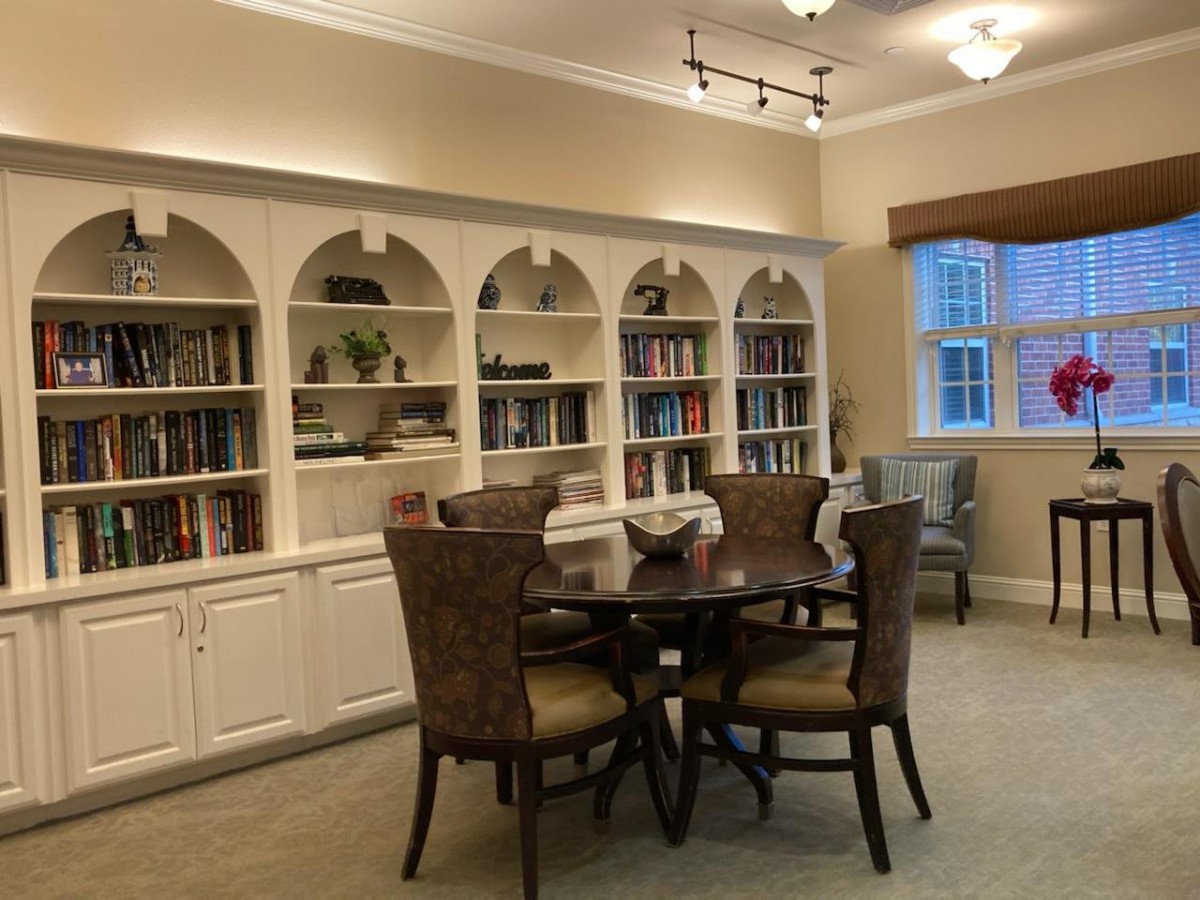 A cozy library room with bookshelves, a round table, and chairs.