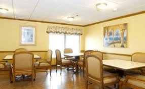 A cozy dining area with tables and chairs, decorated with wall art and natural light from the windows.