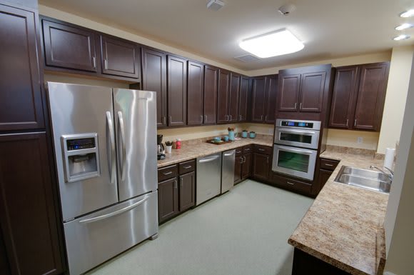 A modern kitchen with dark wood cabinets and stainless steel appliances.