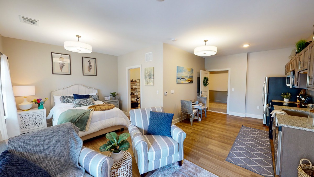 A modern and cozy open-plan bedroom and living area with stylish decor and wood flooring.