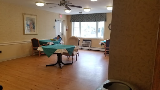 A spacious dining area with tables set for meals, featuring natural light from a large window.
