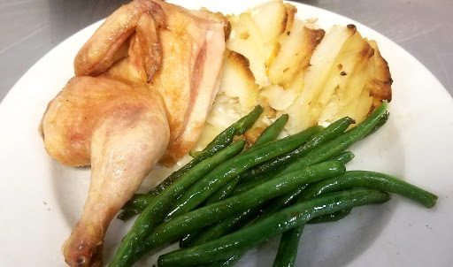 A delicious plate featuring roast chicken, steamed green beans, and golden roasted potatoes.