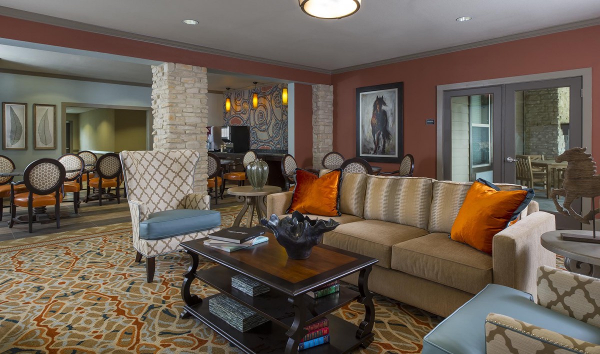 A warm and inviting living room with a striped sofa, accented by orange cushions, a dark wooden coffee table, and artwork on the walls.