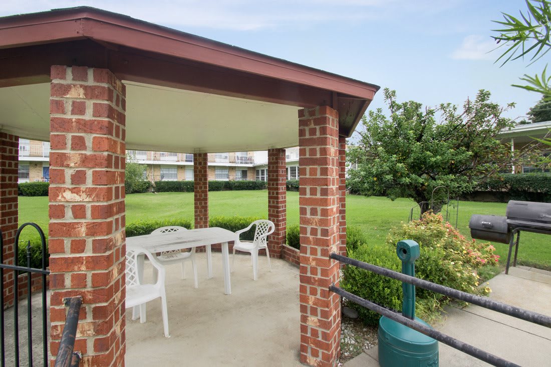 A brick gazebo with white furniture overlooks a lush green landscape.