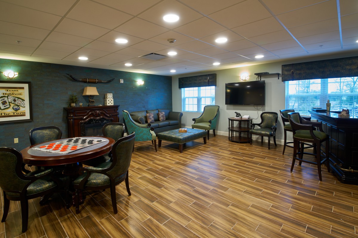 A cozy lounge area with comfortable seating, wooden flooring, and a large television.