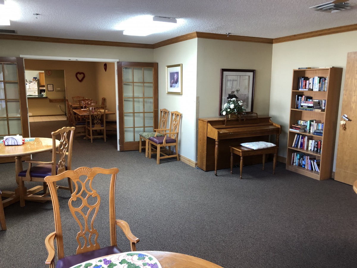 A cozy room with a piano, bookshelf, and seating area.